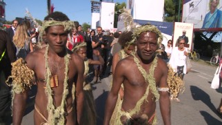 The cast of "Tanna" draws looks as they walk past a "Black Mass" poster at the Venice Film Festival.