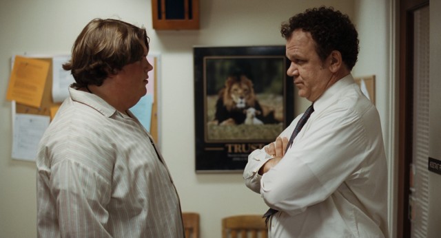 Terri (Jacob Wysocki) and Mr. Fitzgerald (John C. Reilly) face off, paralleling a lion and lamb poster advocating trust.