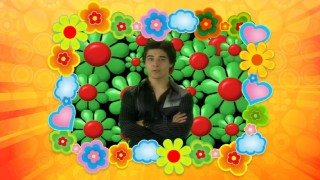 Wilmer Valderrama pops a trivia question amidst green and red flowers.