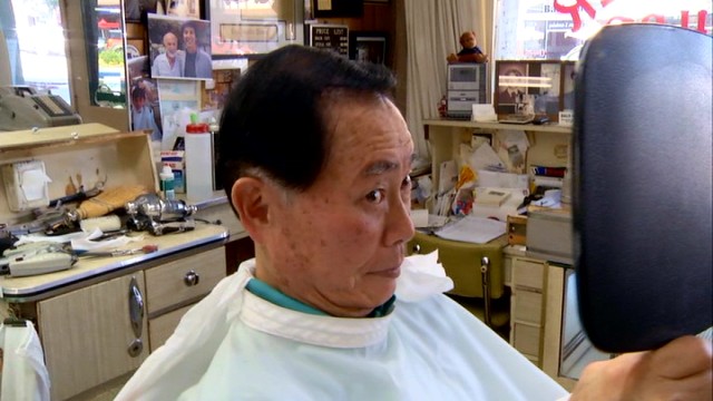 George Takei holds a mirror up to himself after a haircut from his high school classmate and longtime barber in "To Be Takei."