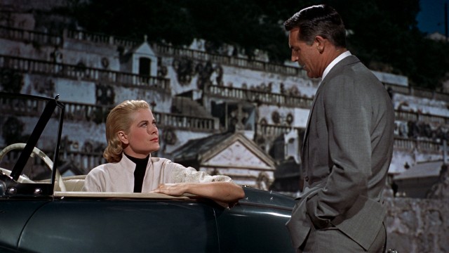 Francie (Grace Kelly) and Robie (Cary Grant) have a post-burial talk in front of a very phony cemetery backdrop.