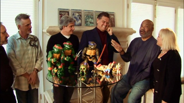 Teenage Mutant Ninja Turtle voice actors gather around a table holding toy likenesses of their characters in "Turtle Power: The Definitive History of the Teenage Mutant Ninja Turtles."