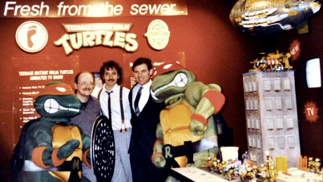 Teenage Mutant Ninja Turtles creators Peter Laird and Kevin Eastman and licensor Mark Freedman pose for a picture with a costumed Michelangelo and Raphael in "Turtle Power."