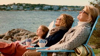 Three generations of Haines women (India Ennenga, Meg Ryan, and Candice Bergen) soak in the sun by a scenic New England coast and lighthouse.