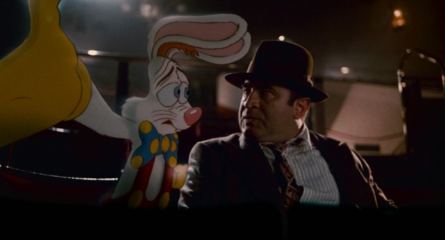 Roger Rabbit and Eddie Valiant (Bob Hoskins) mull over the facts in a theater showing a Goofy short and newsreels.