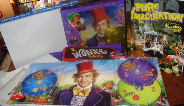 A look at the contents of the Willy Wonka and the Chocolate Factory 40th Anniversary Blu-ray + DVD Ultimate Collector's Edition: three discs, a big box, a book, an envelope of document reproductions, a Wonka Bar tin, a scented eraser, a sweepstakes golden ticket, and scratch-n-sniff pencils.