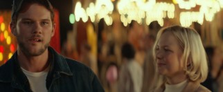 Travis (Jeremy Irvine) shows his candy striper girlfriend Lori (Adelaide Clemens) his sharpshooting skills at a carnival attraction.
