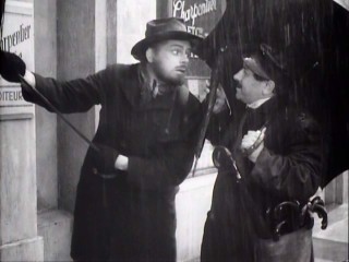 Having just been informed of his new financial comfort, French writer Emile Zola is more than willing to buy an umbrella in falling rain.
