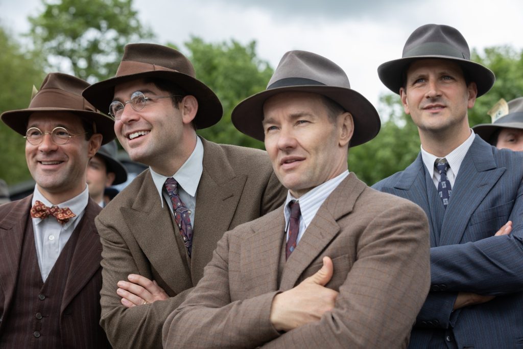 "the boys in the boat" are watched, reported upon, and coached by white men in suits and hats (led by joel edgerton, second from right).